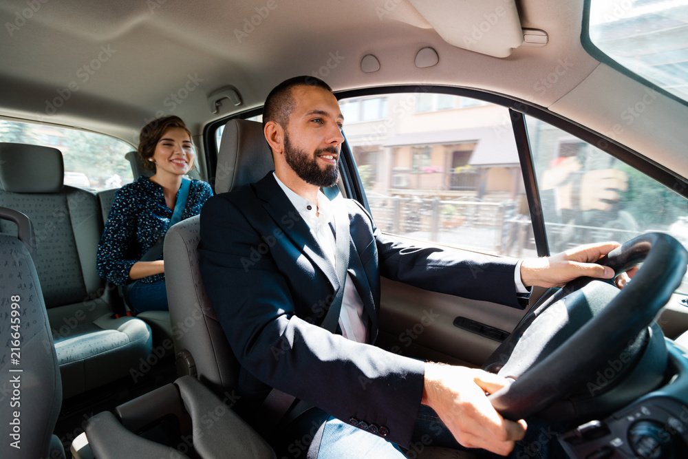 Taxi driver sitting in a car with businesswoman